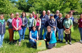 Gruppe von Menschen posiert im Freien mit einem Schild "Vogelfreundlicher Garten" des LBV.