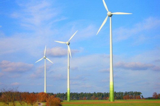 Drei Windräder auf einem Feld, dahinter Wald | © R. Brode