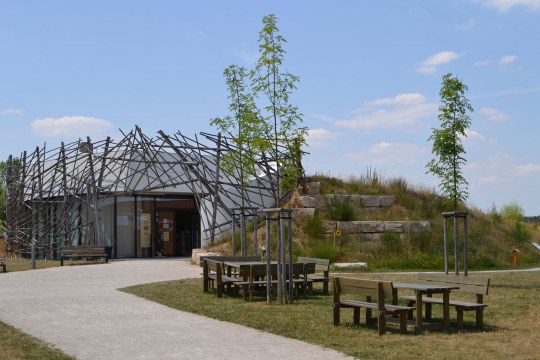 Umweltstation am Rothsee. Links das Gebäude, wo ein gepflasterter Weg hinführt. Rechts befindet sich eine Wiese mit zwei Tischen und Bänken drumherum. Außerdem neu gepflanzte Bäume | © L. Hauselt