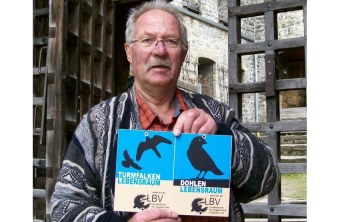 Adolf Geismayr mit der verliehenen Plakette "Lebensraum Kirchturm" vor der ausgezeichneten Burgruine Sulzberg | © LBV