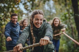 Eine fröhliche Gruppe zieht gemeinsam an einem Seil im Wald, symbolisiert Teamgeist beim LBV-Ausflug. | © stock.adobe.com