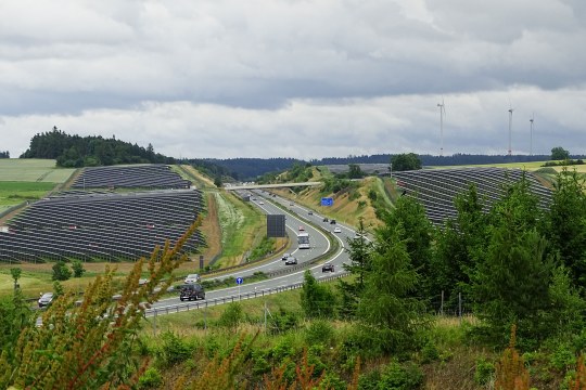 Autobahn umringt von Solarzellen, in der Fernen Windräder | © Peter Bria