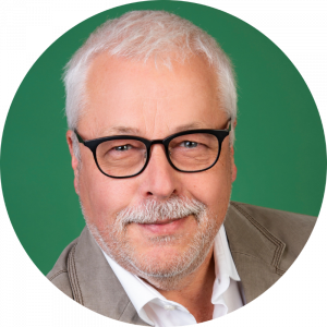 Ein lächelnder Mann mit Brille vor einem grünen Hintergrund, engagiert beim Landesbund für Vogel- und Naturschutz in Bayern e. V.