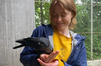 Eine Frau in Regenstauf hält einen Vogel in der Hand und lächelt, während sie sich dem Naturschutz widmet.