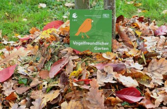 Plakette "Vogelfreundlicher Garten" im Herbstlaub | © Peter Bria