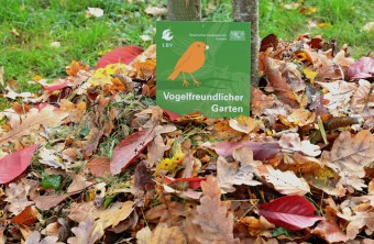 Plakette "Vogelfreundlicher Garten" im Herbstlaub | © Peter Bria