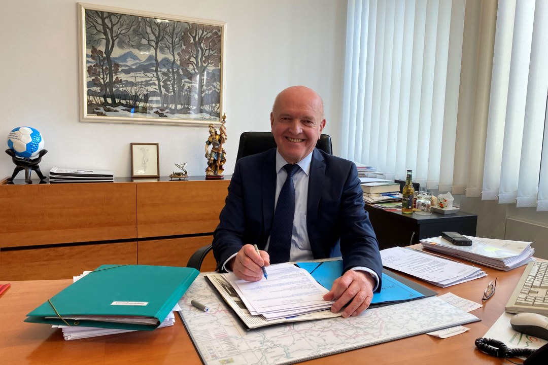 Landrat Thomas Habermann sitzt an seinem Schreibtisch und lächelt in die Kamera | © Regina Fuchs