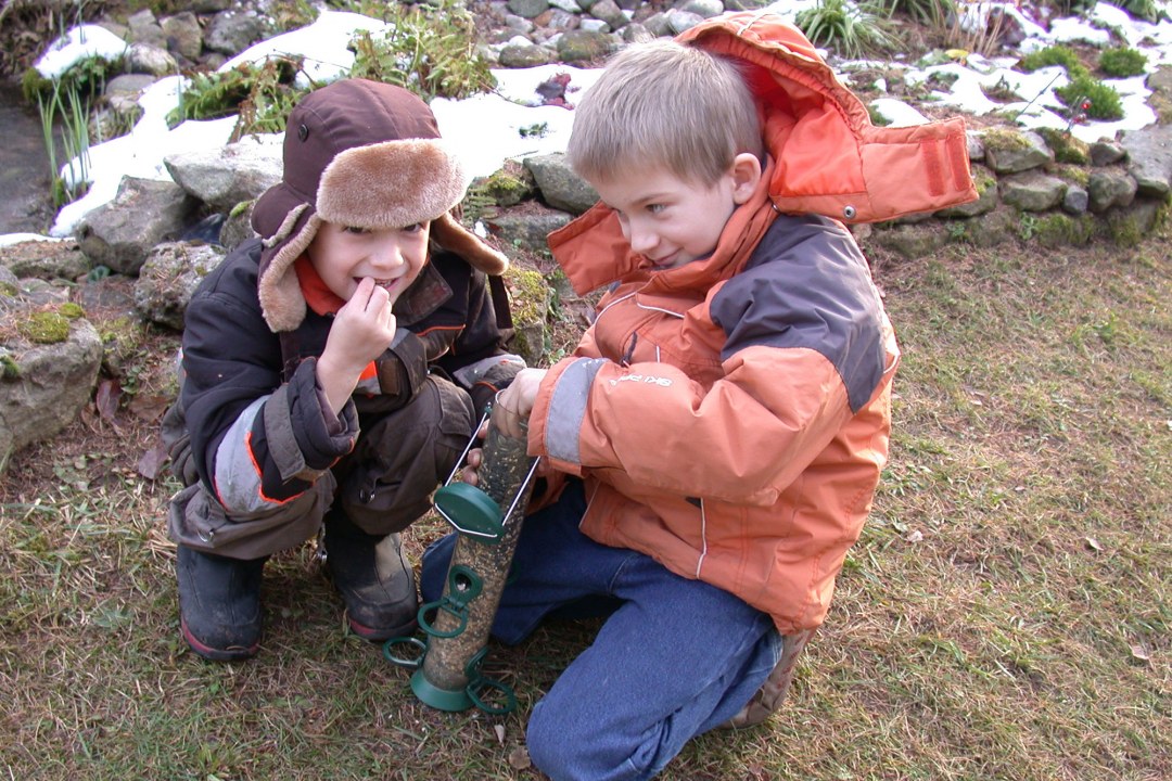 Zwei Kinder sitzen am Boden mit einer gefüllten Futtersäule in der Hand | © Birgit Helbig