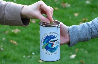 Jemand steckt Geld in die Sammeldose des LBV | © Carola Bria