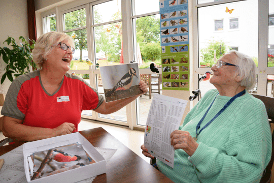 Betreuerin zeigt Seniorin Bild von Specht | © Tobias Tschapka