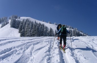 Skitourengeher gehen hintereinander im Schnee auf einem Berg | © Henning Werth
