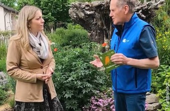 Ein Mann im LBV-Outfit spricht in einem Garten mit einer Frau über Naturschutzthemen.