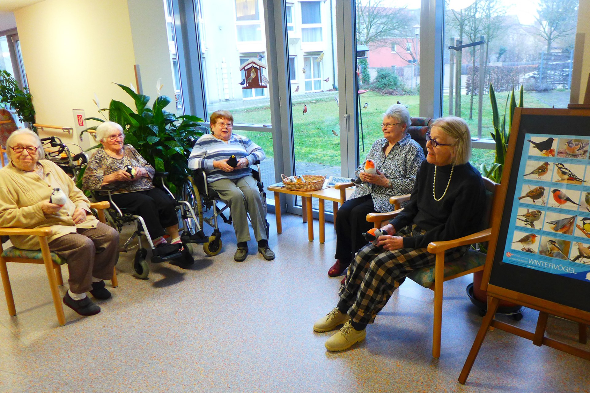 Mehrere Seniorinnen sitzen zusammen vor dem Vogelfenster unterhalten sich | © Burkhard von Seckendorff Heim