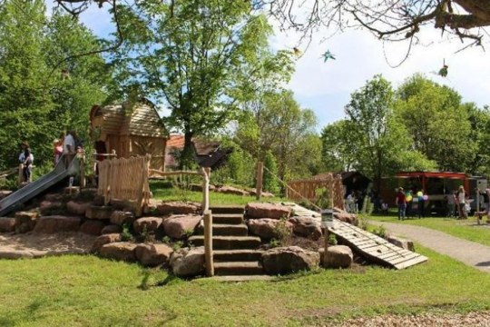 Kita Haus für Kinder uns Familien „Der gute Hirte“ in Illesheim, man sieht einen Spielplatz im Grünen, die Sonne scheint