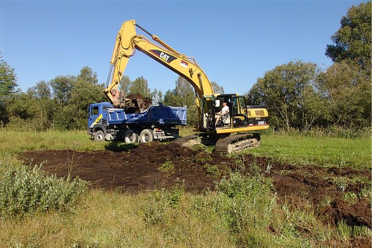 Ein gelber Bagger hebt eine flache Mulde aus | © C. Stoll
