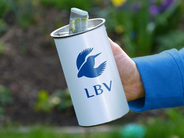 Jemand steckt Geld in die Sammeldose des LBV | © Carola Bria