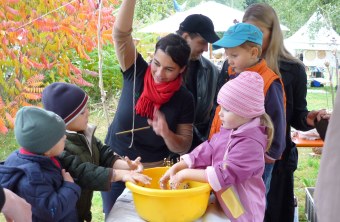 Vier Kinder lernen von einer erwachsenen Frau, wie sie Vogelfutter selbst herstellen können | © Doris Lundgreen