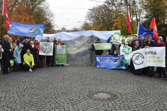 Demonstranten vor dem Bayerischen Landtag der Umwelt- und Naturschutzverbände. Man sieht ein Bild vom Riedberger Horn und daneben Banner von LBV, Bund Naturschutz, Cipra und DAV | © Christoph Stache