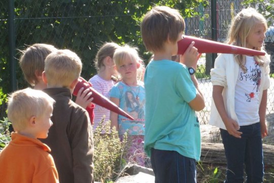 Kinder mit Pappschnäbeln spielen Störche nach | © Christian Stierstorfer