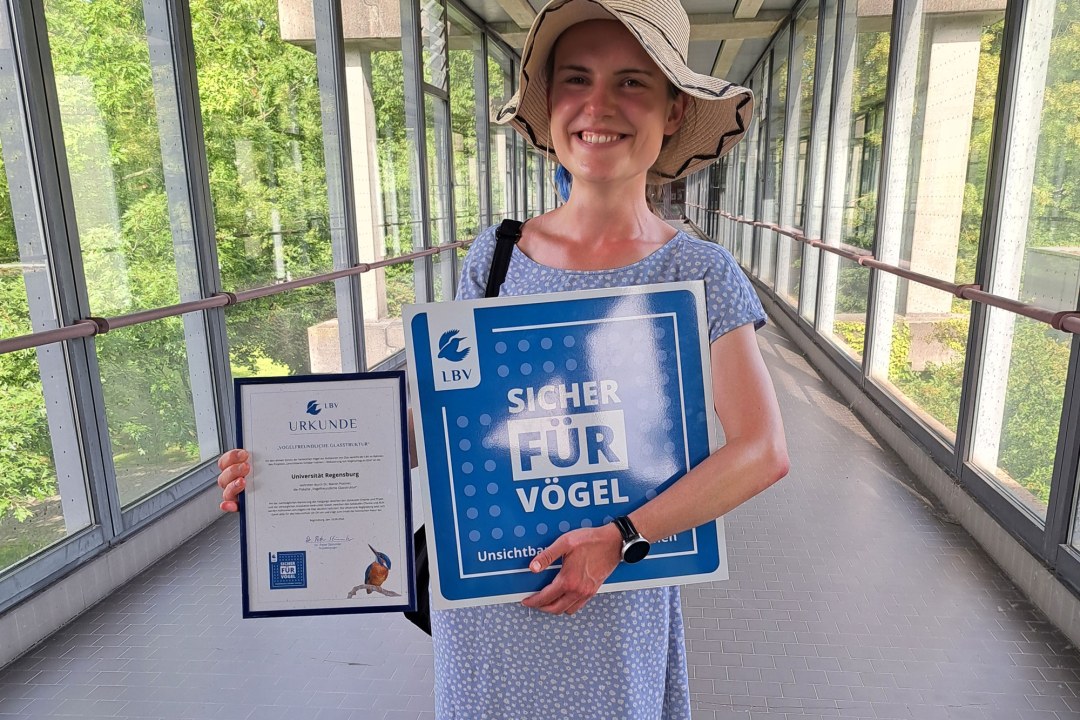 Elisabeth Hofer mit der Auszeichnung „Vogelfreundliche Glasfläche“ im nachgerüsteten Kaltgang der Uni Regensburg | © Dr. Peter Stimmler