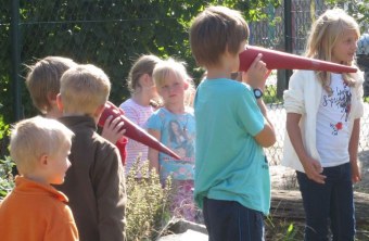 Kinder mit Pappschnäbeln spielen Störche nach | © Christian Stierstorfer