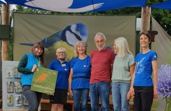 Eine Gruppe von Menschen steht gemeinsam an einem Infostand der LBV zur Landesgartenschau 2025.