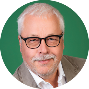 Ein lächelnder Mann mit Brille vor einem grünen Hintergrund, engagiert beim Landesbund für Vogel- und Naturschutz in Bayern e. V.