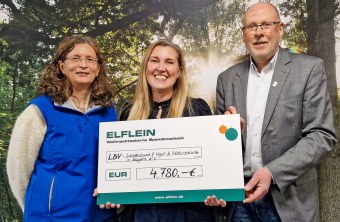 Drei Personen lächeln stolz, während sie einen Scheck über 4.780 Euro für den LBV in Händen halten.